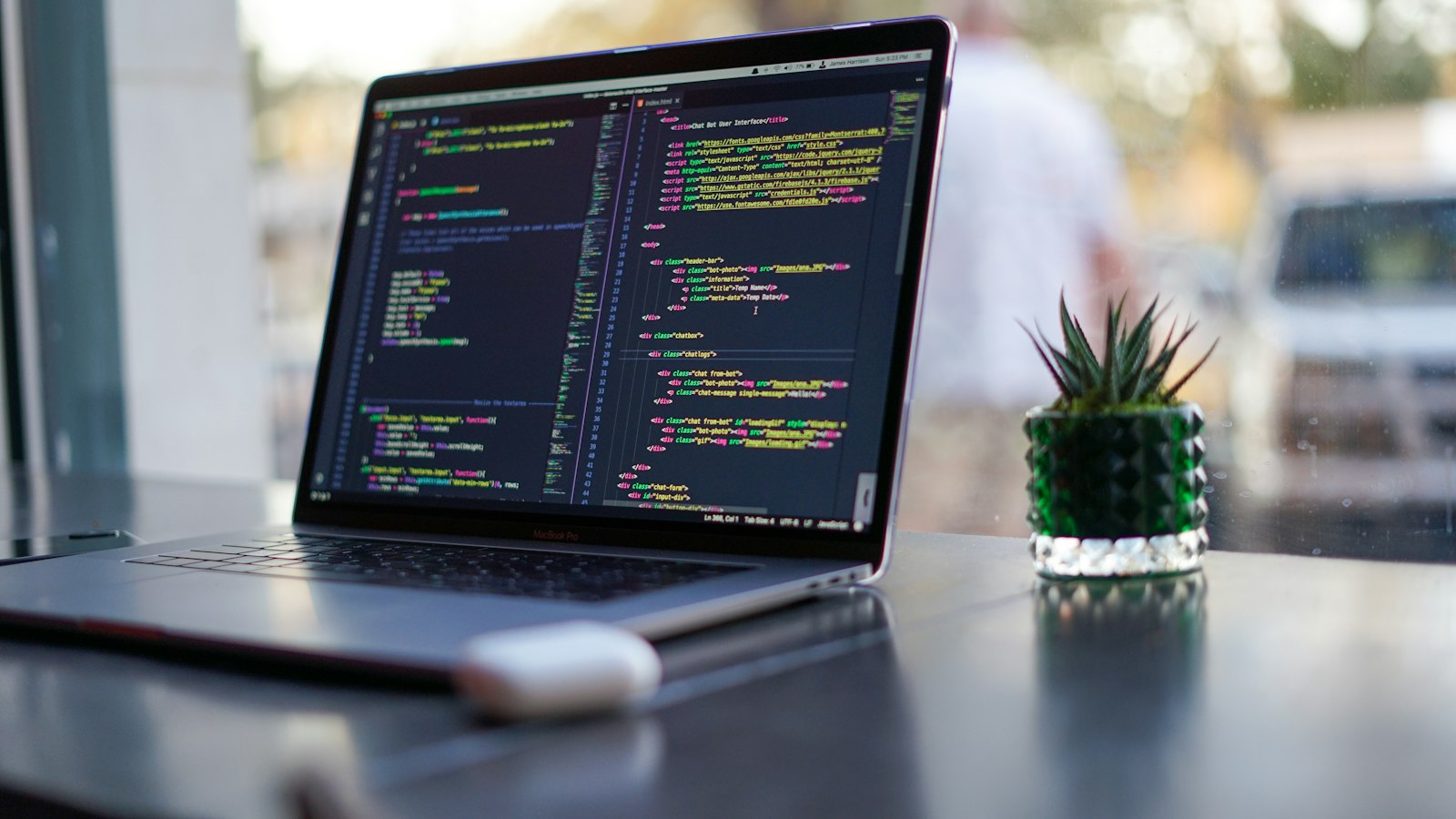 Laptop met code op het scherm naast een kleine cactus